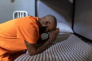 man in orange t shirt praying on bed